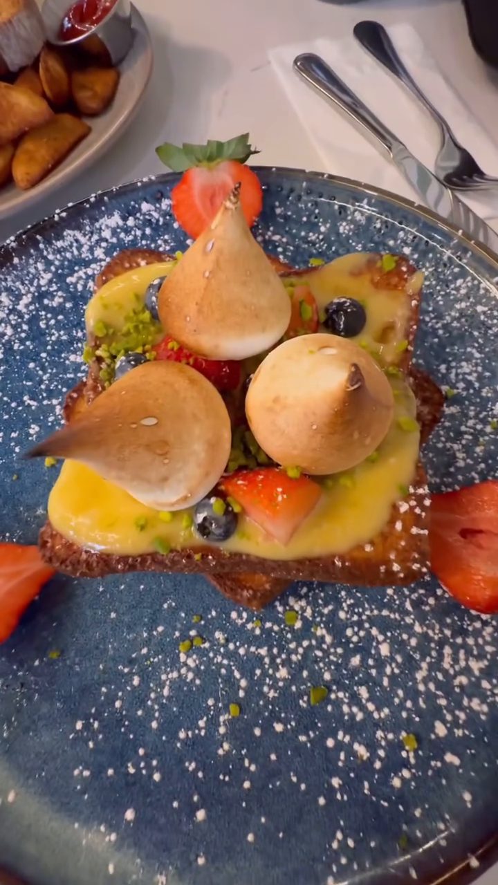A dessert plate with meringue, fruit and custard on a blue dish